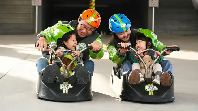 大人帶小孩共乘斜坡滑車的畫面