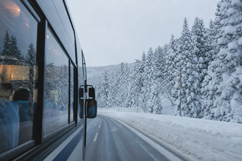八甲田號巴士行經雪季國道，車窗外是被雪包覆的針葉林