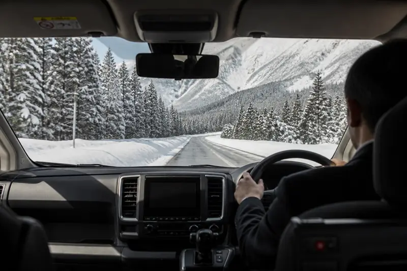 司機駕駛的專車行駛於青森雪季道路，車窗外是雪景