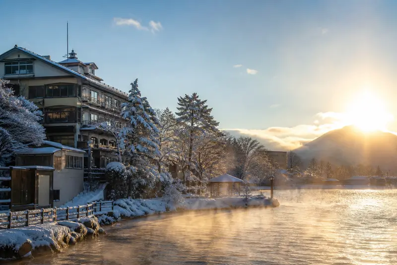 北海道冬季清晨雪景，溫泉街與湖面蒸氣，陽光剛升起
