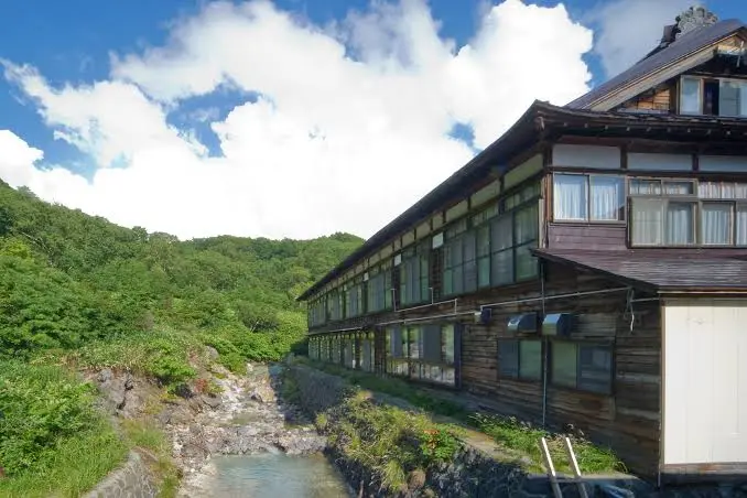 酸ヶ湯溫泉旅館冬季外觀，木造建築幾乎被四公尺深的積雪包圍