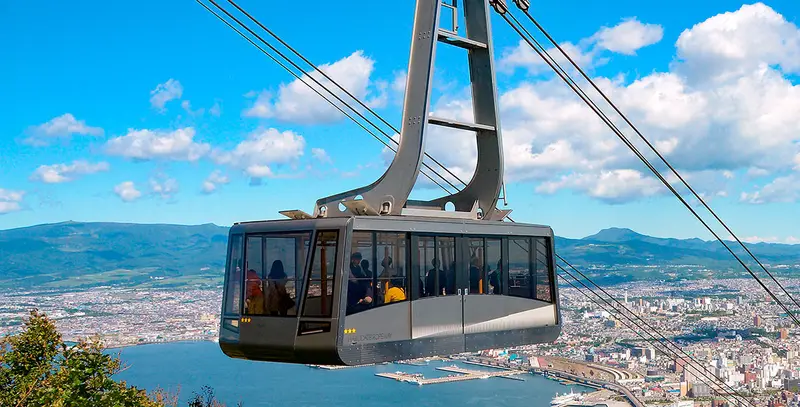 函館山纜車車廂緩緩上行，窗外是漸暗的市街與海灣燈火