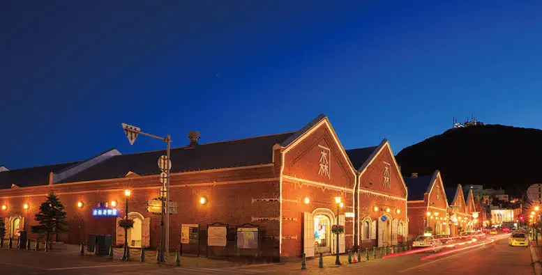 金森紅磚倉庫的港灣夜間點燈，磚牆與燈影倒映在水面