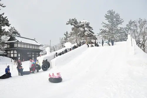 弘前公園四の丸的大雪像與大型雪滑梯，親子在雪中遊玩