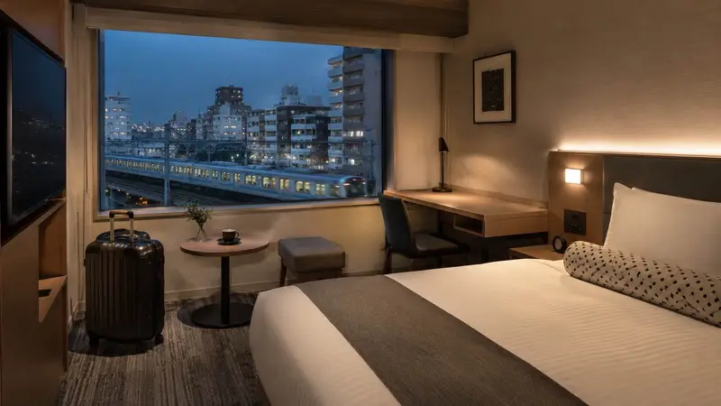 日本市區飯店房間與窗外夜景，象徵演唱會自由行住宿選擇。