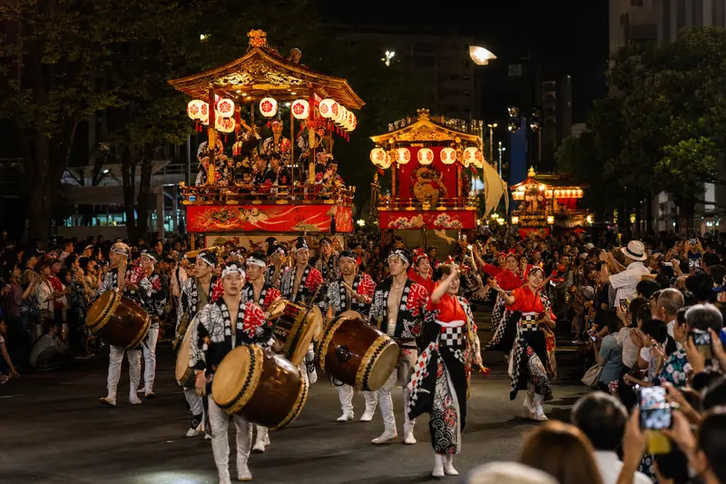日本傳統祭典遊行中，山車、太鼓與舞者展現熱鬧氣氛。