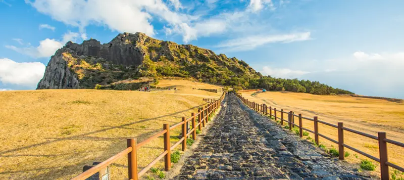 城山日出峰全景，綠色火山口與環繞的海岸線