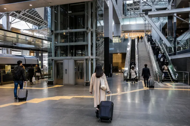 大阪或京都大型車站內旅客拖著行李尋找電梯與轉乘出口。
