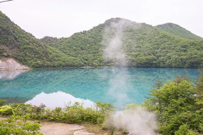 潟沼強酸性火口湖的藍綠色湖面與環湖秋色
