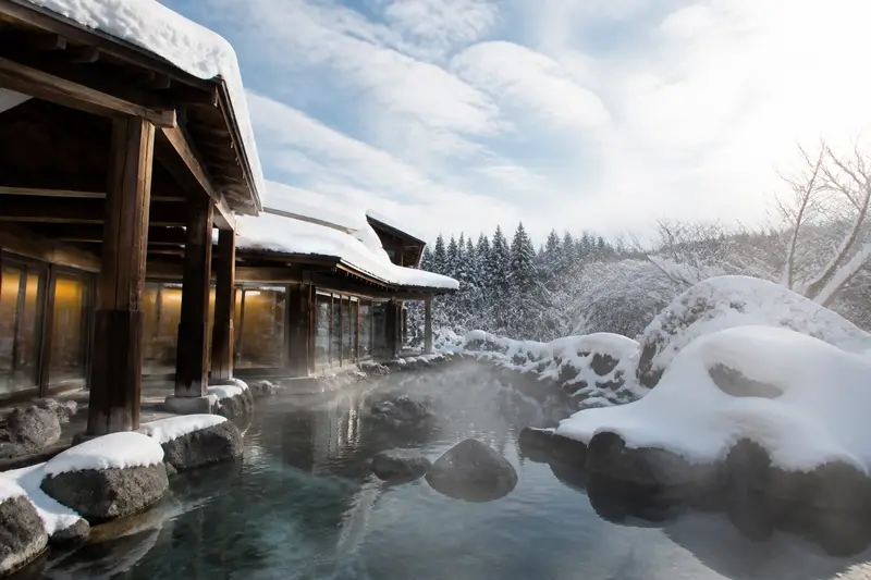 二世古湯本溫泉大湯沼，乳白色硫磺泉源頭冒著蒸氣，雪景環繞