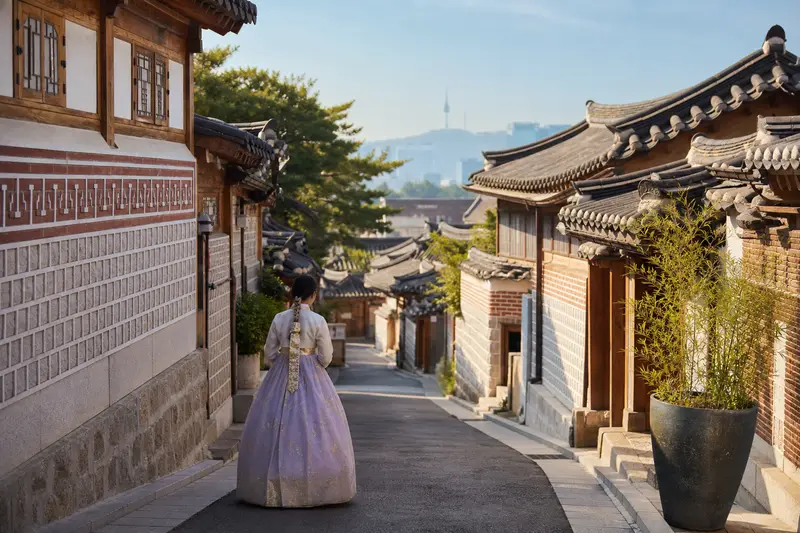 穿韓服的旅人走在北村韓屋村石牆巷弄間。