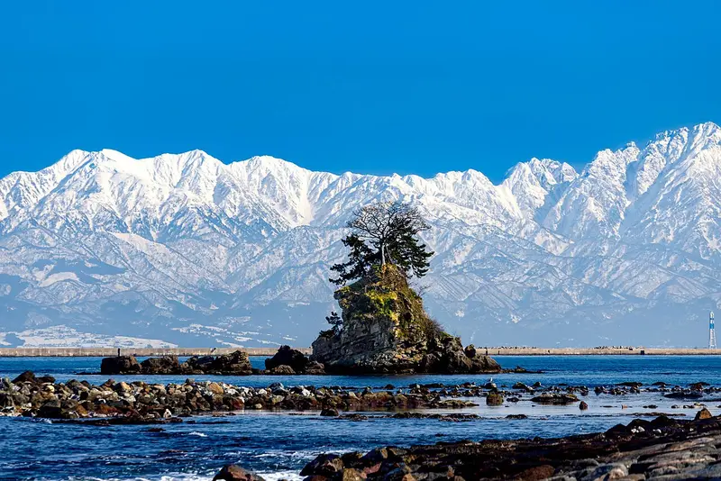 雨晴海岸的女岩與海面上浮現的立山連峰